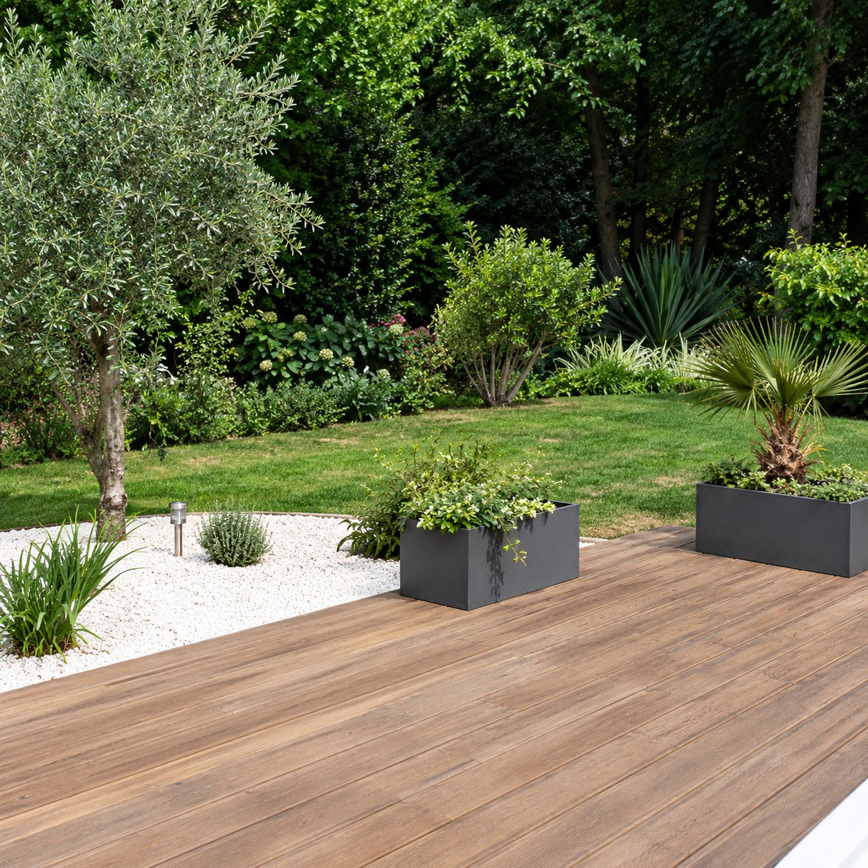 Une terrasse en bois donne sur un jardin paysager avec des jardinières, des arbustes et des galets blancs.